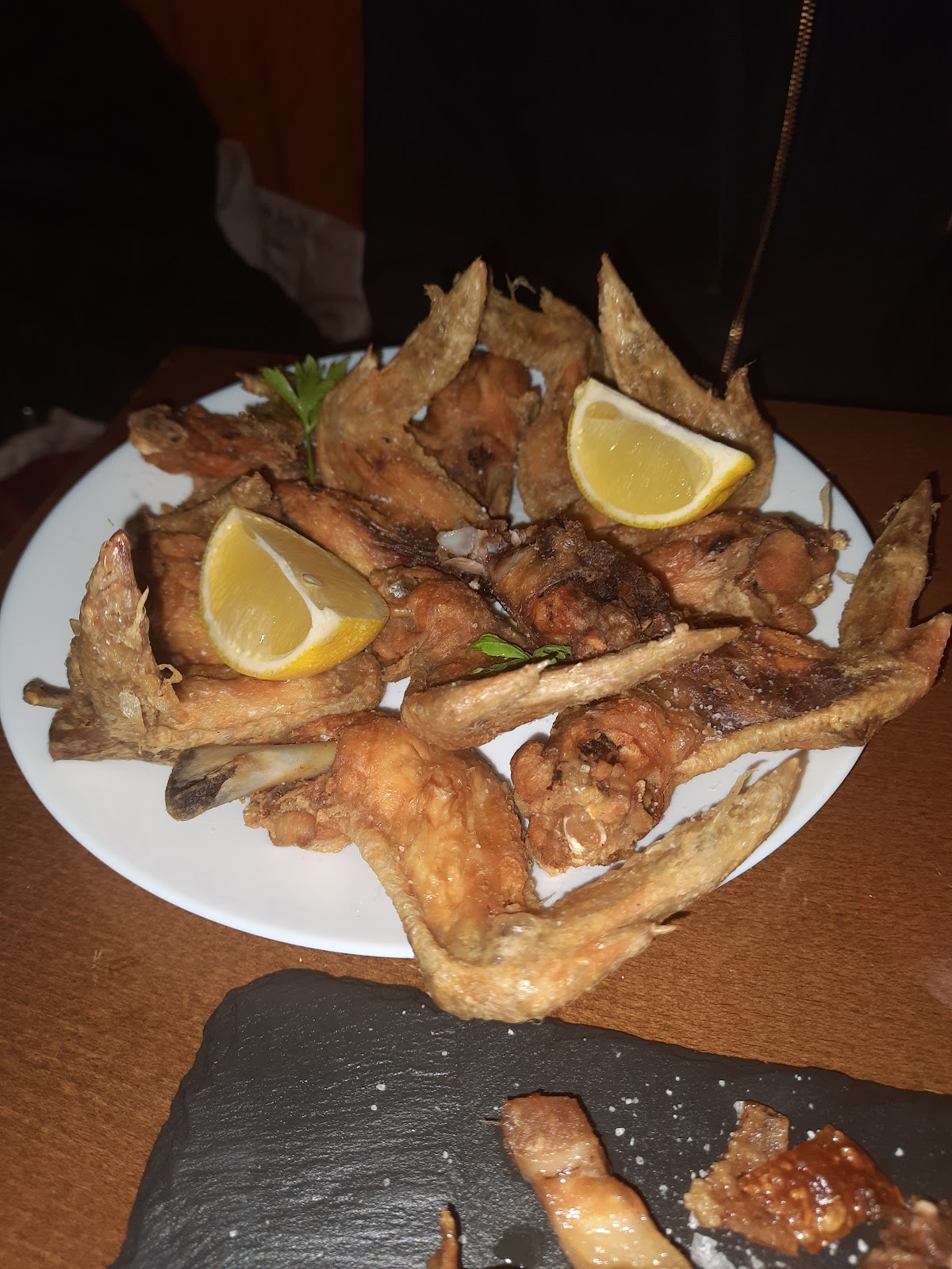 Pescado frito. Un plato con varios trozos de pescado frito, decorado con rodajas de limón.