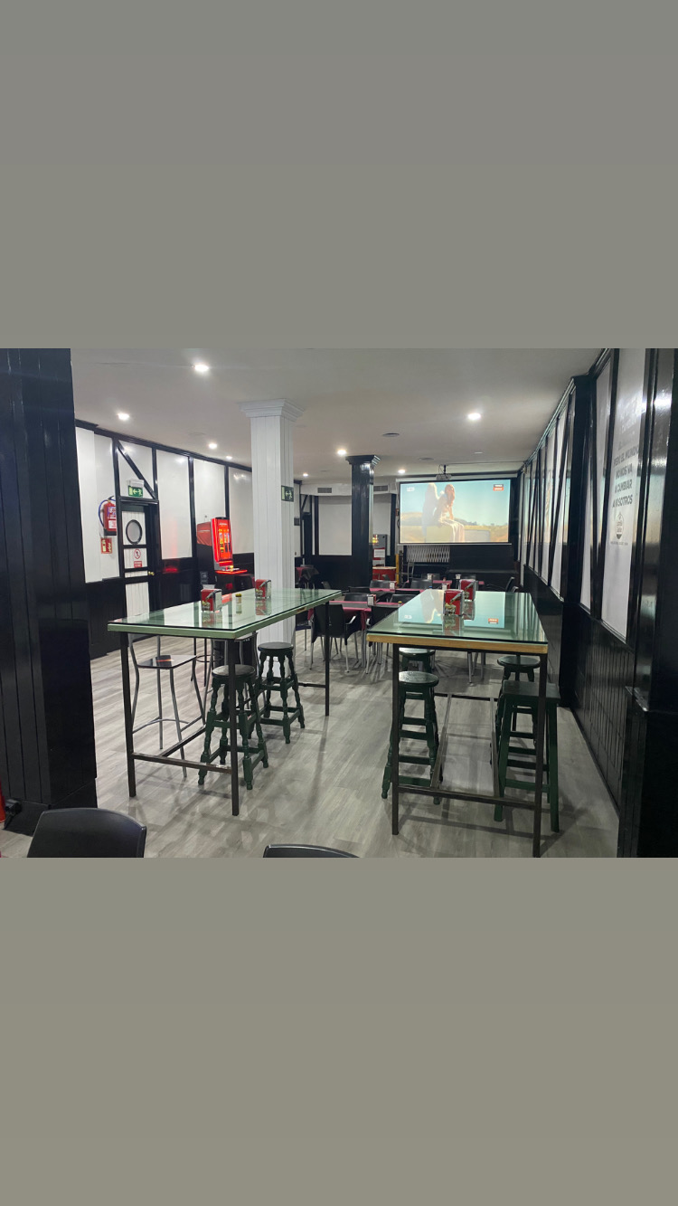Espacio de comedor. Una vista del comedor con mesas altas y sillas, y una pantalla grande proyectando contenido.